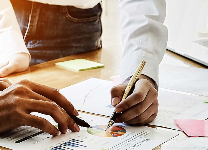 Two hands holding pens pointing to graph on paper