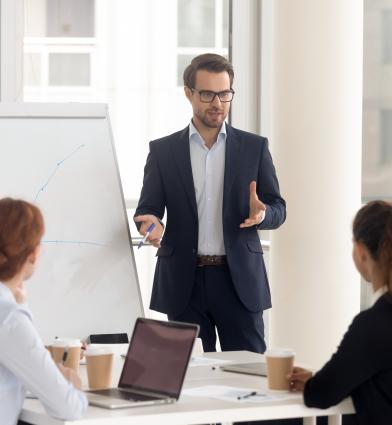 man presenting to professionals on white board 